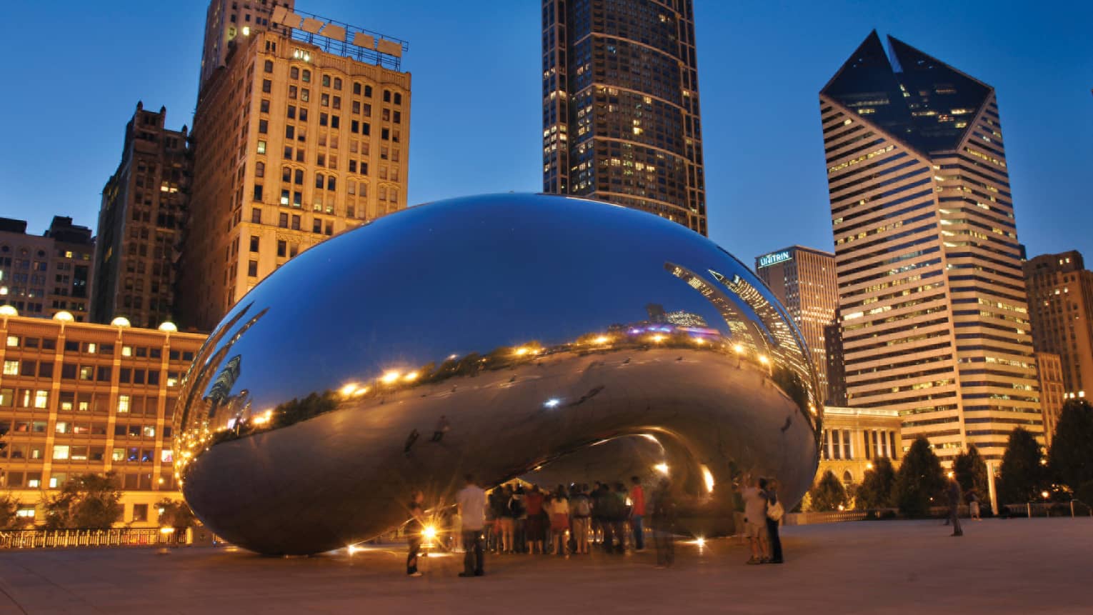 Cloud Gate public sculpture reflecting lights at dusk, Chicago skyscrapers in background