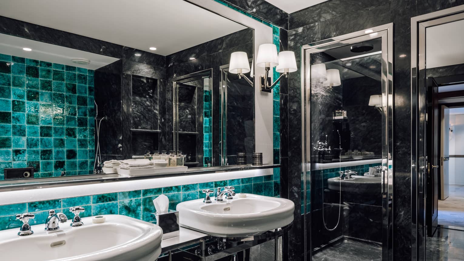 Black marble bathroom with turquoise accent tiles, two sinks, full-width mirror