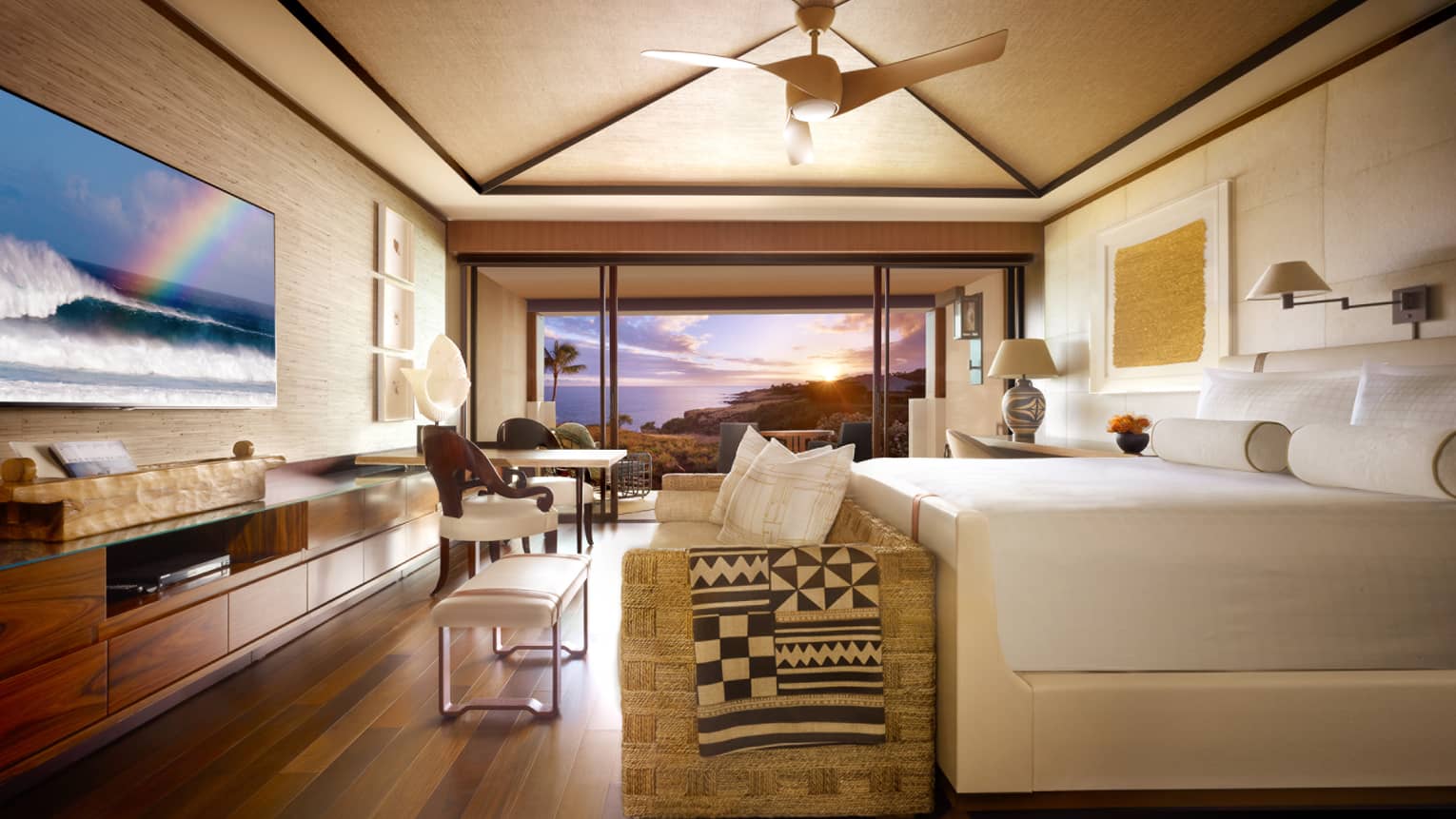 Partial Ocean-View Room bed, wicker sofa at foot with throw blanket, TV screen displaying waves, rainbow