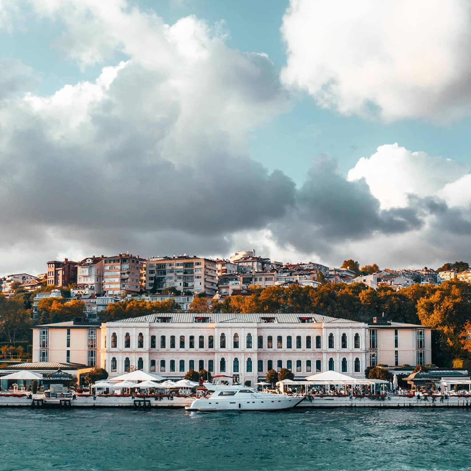 View from water to historic Istanbul Four Seasons hotel building under dramatic sky, clouds