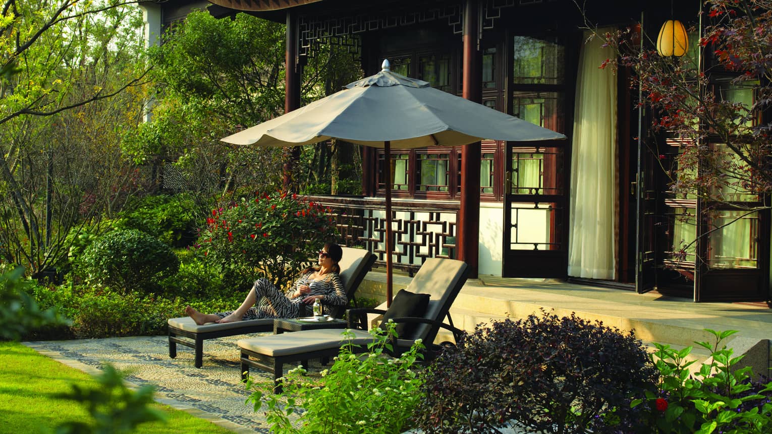 Royal West Lake Suite woman in zebra-striped outfit under umbrella on patio lounge chair