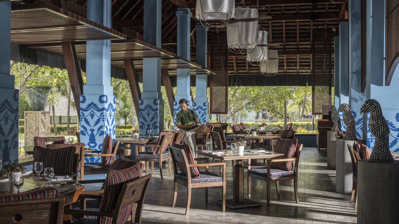 A server in Lower Serai restaurant Dining room sets the table