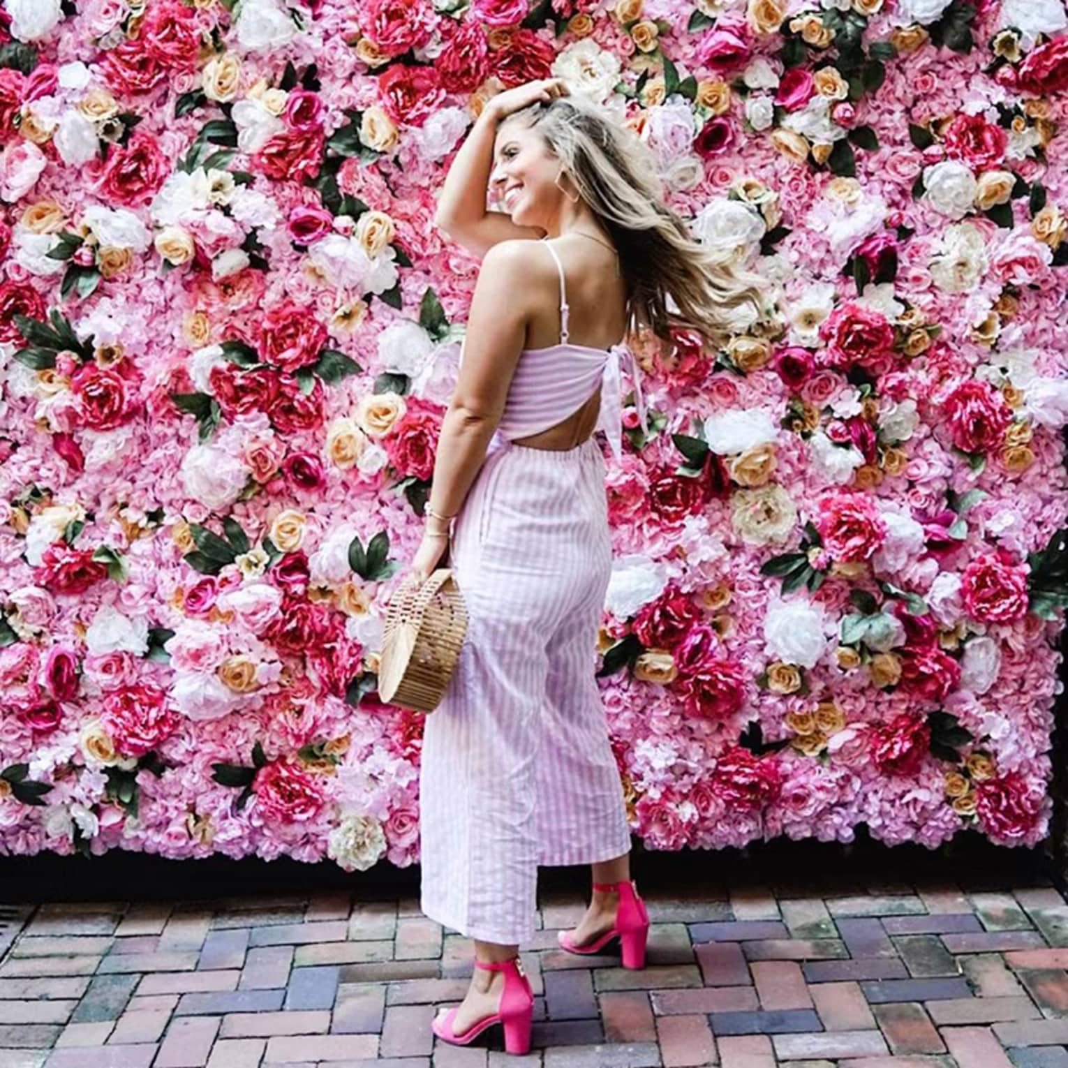 Smiling woman poses in front of wall of roses