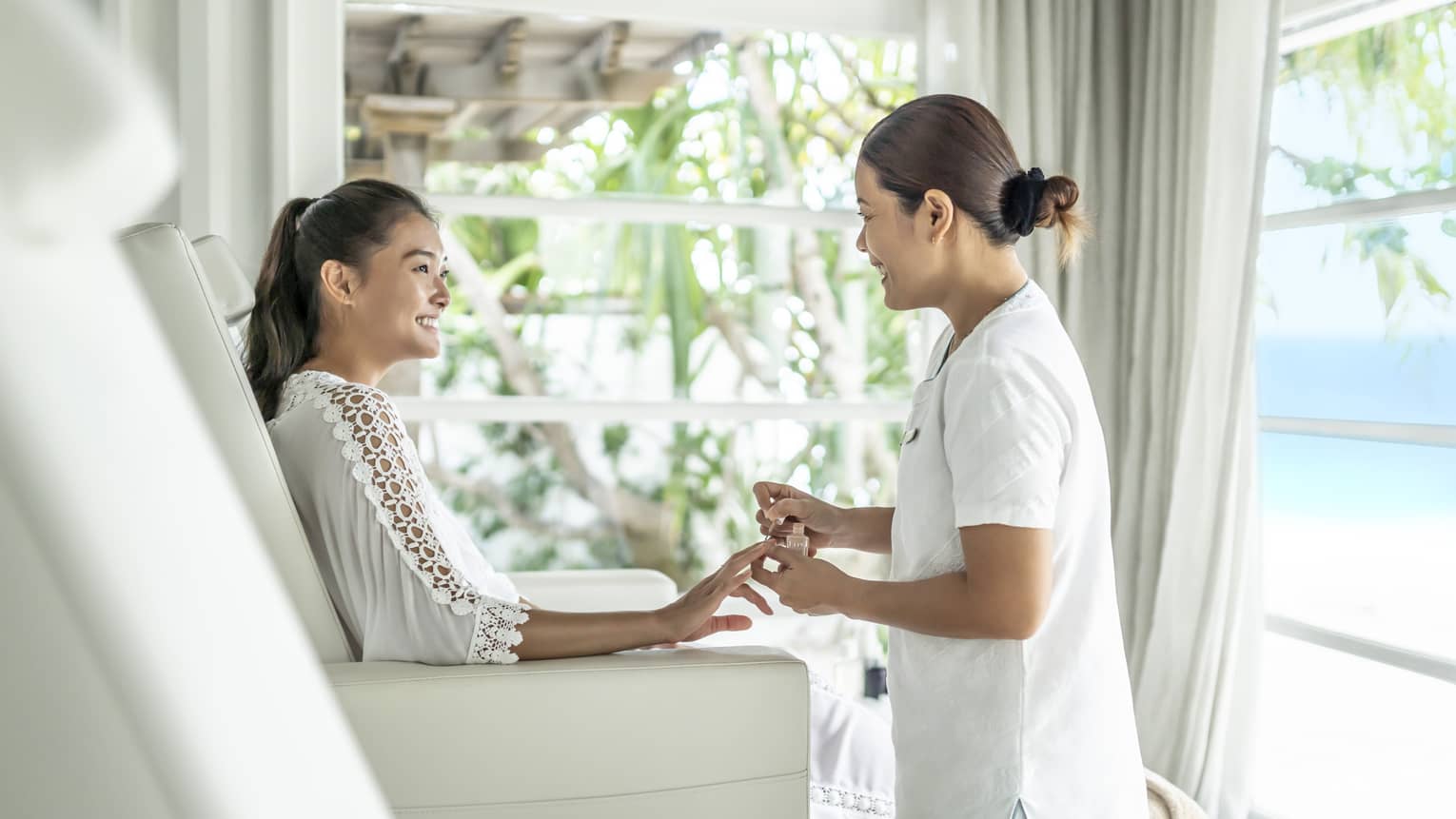 A four seasons guest gets her nails down while sitting in a white leather salon chair 