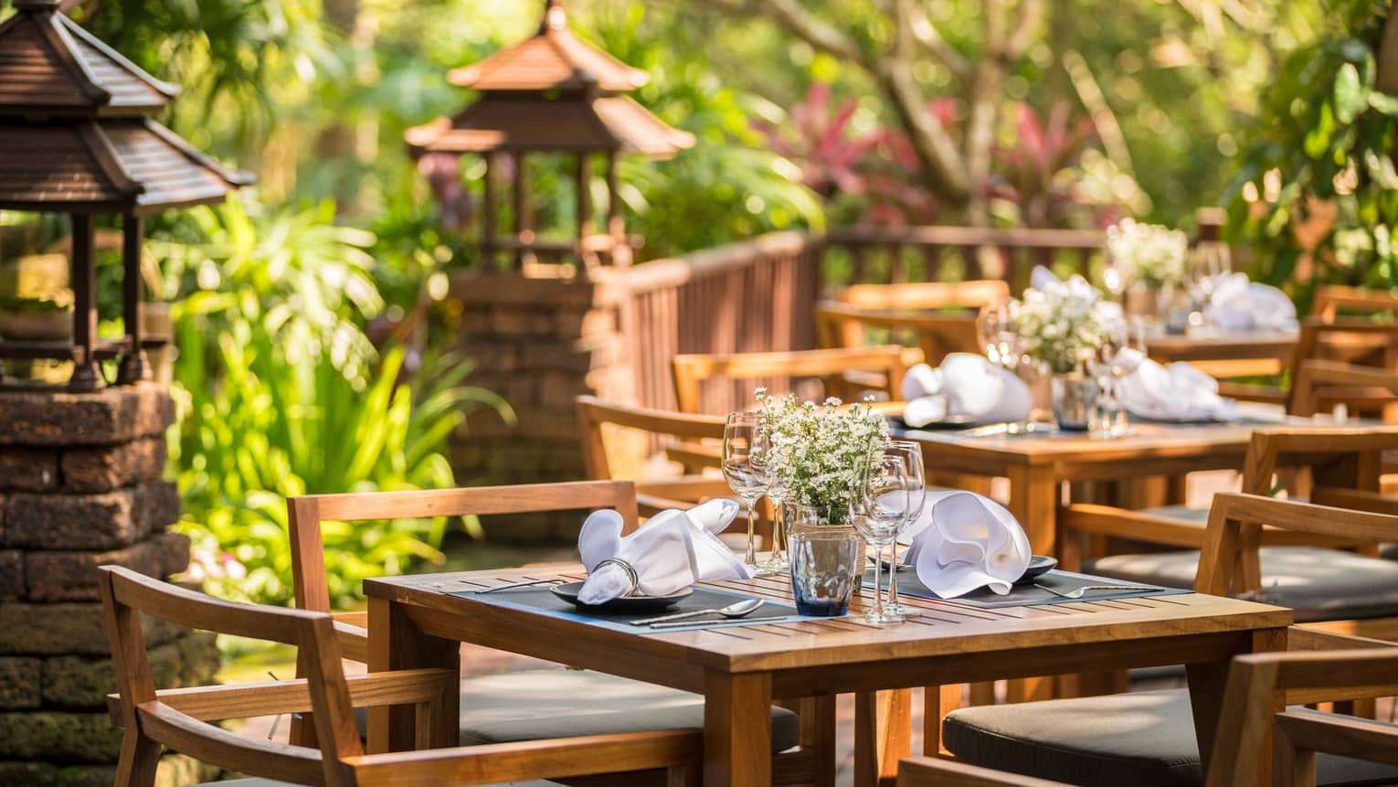 Wood dining tables on sunny patio near brick posts with small wood gazebos