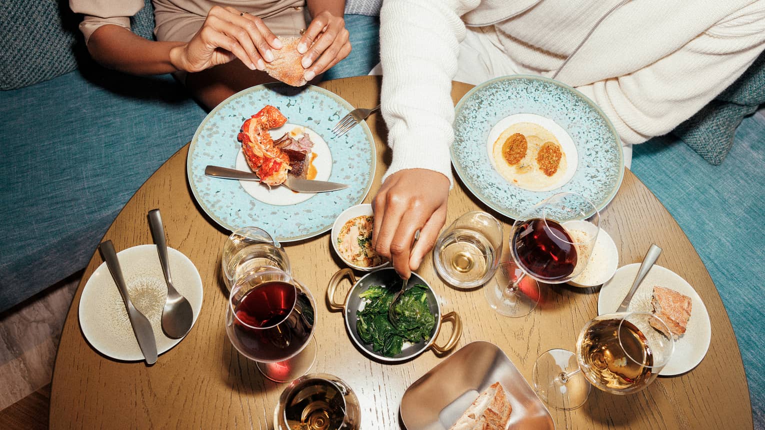 Two people sitting at a table with various food and drinks.