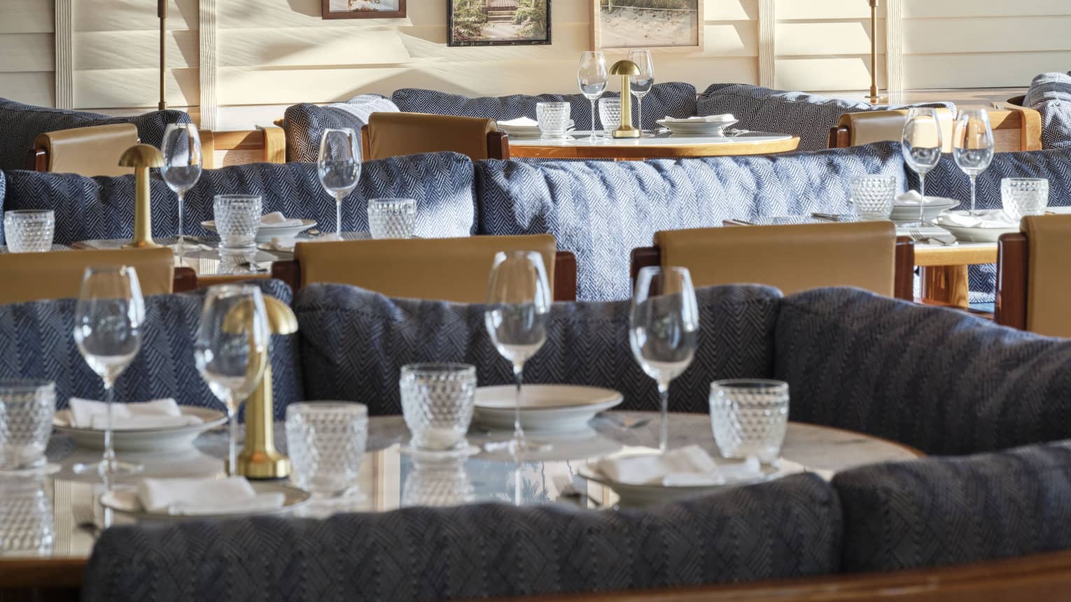 The interior of a restaurant with large booths with blue cushions and art on a wall.