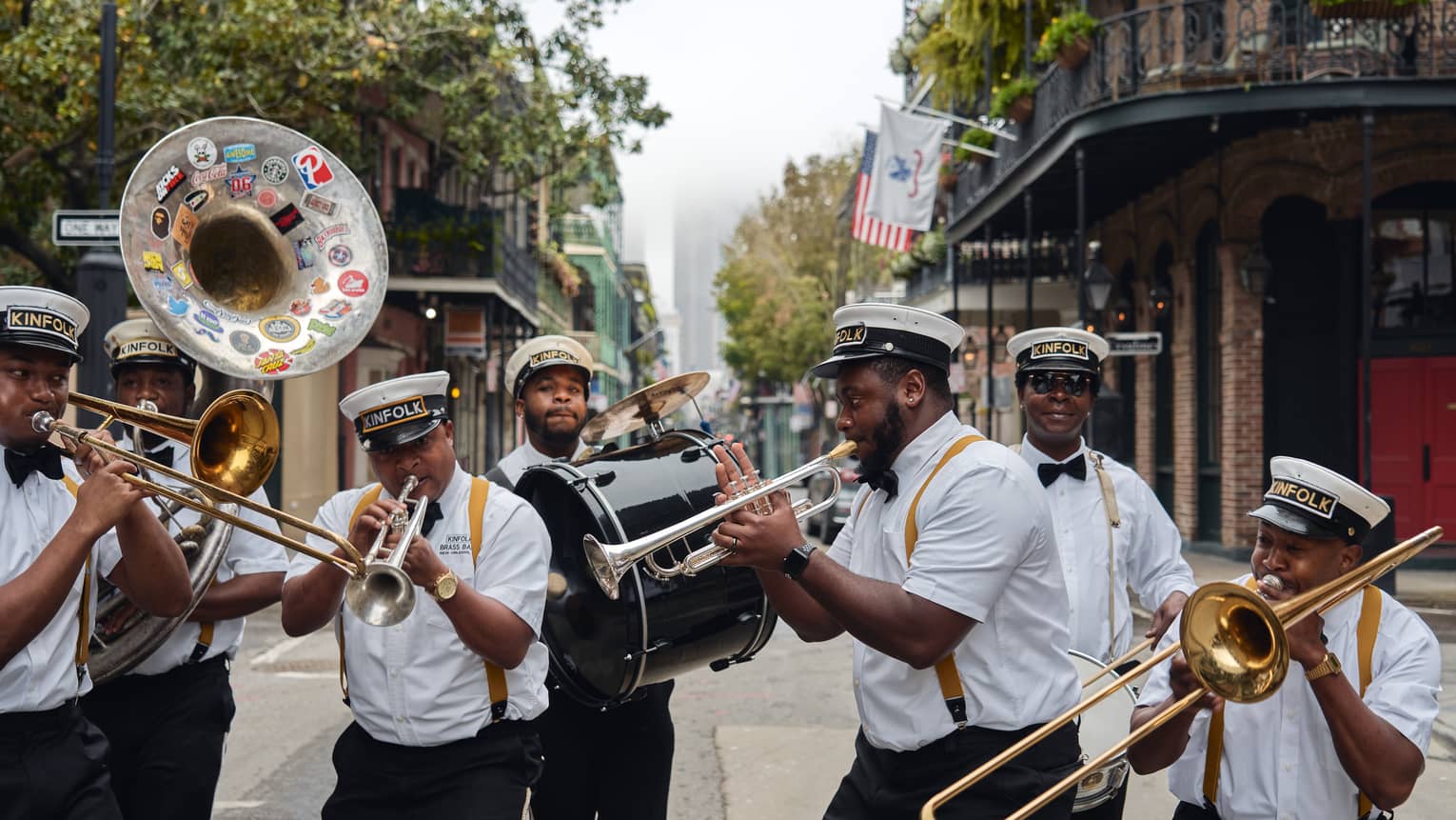 A group of men playing horned instruments while walking down a street.