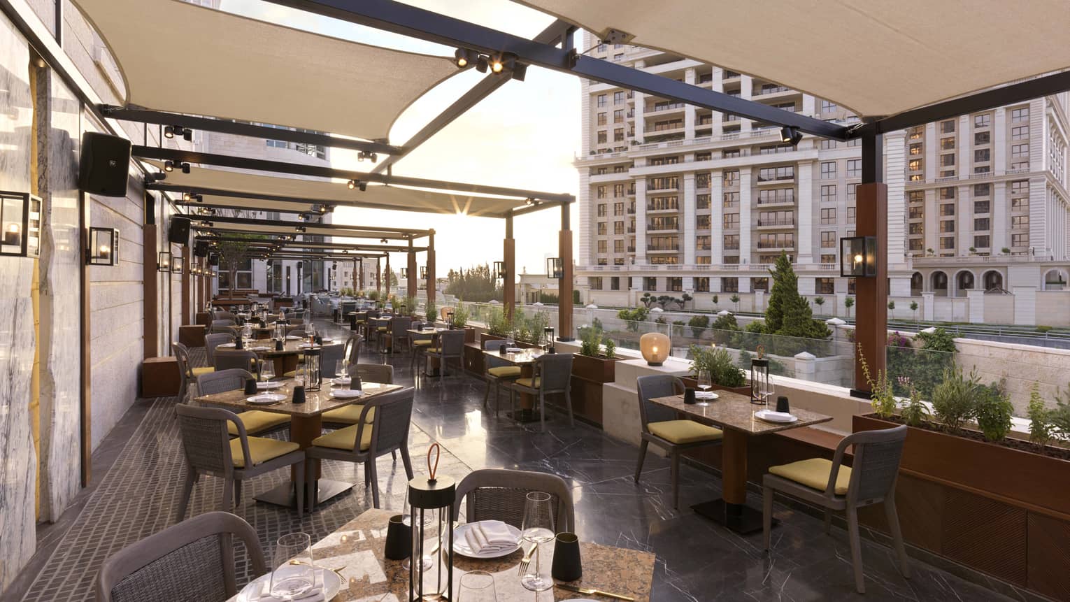 Restaurant terrace overlooking a city with sun shades over the tables