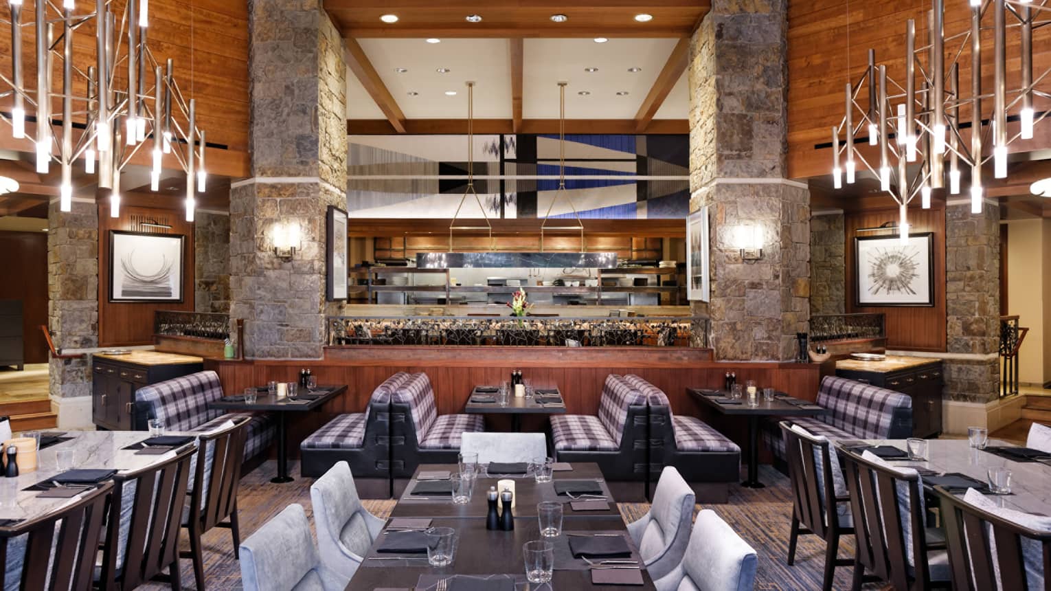 Dining room with rectangular tables and booths, kitchen prep area in the background 