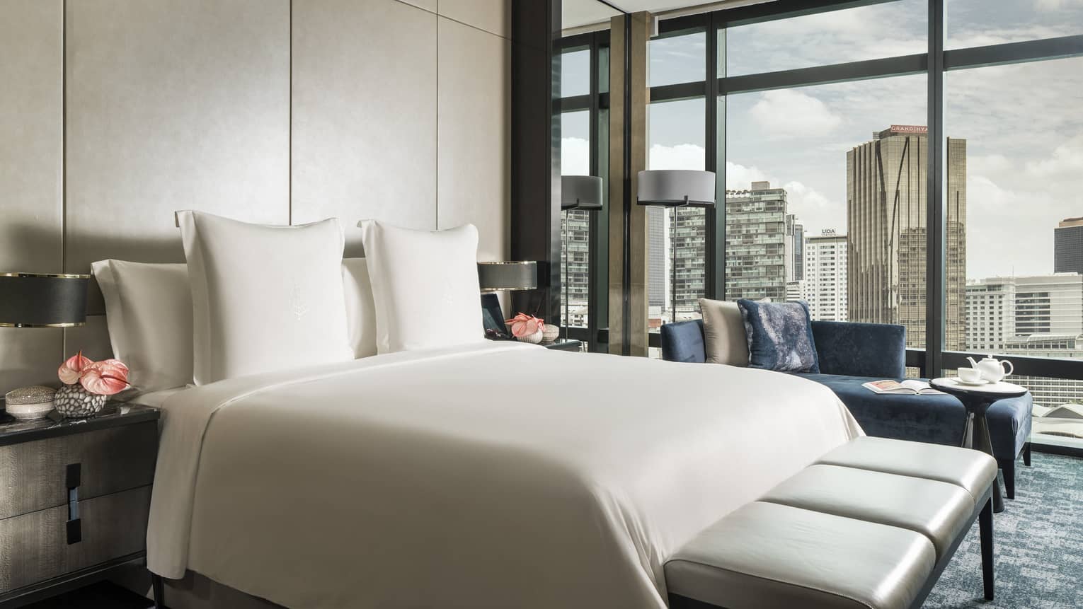 Bed and leather bench in front of padded wall, floor-to-ceiling wall of windows