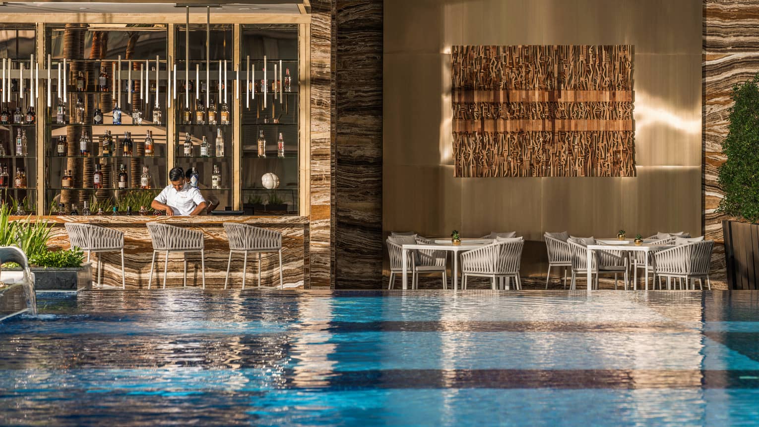 Pool bar and grill with view of pool and bartender