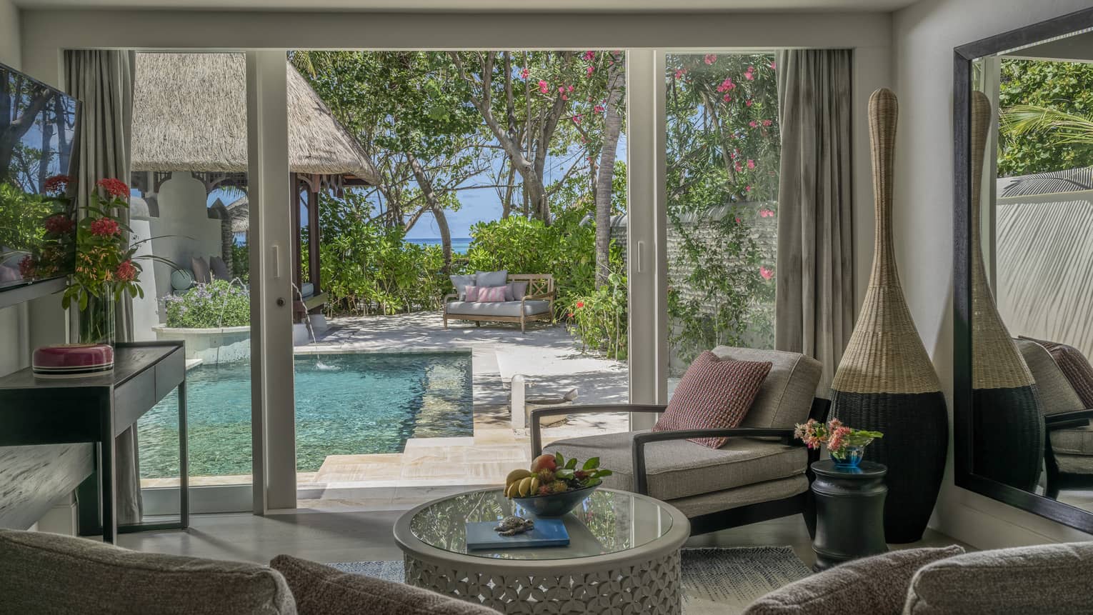 Living room opening to pool deck, with beach in the distance