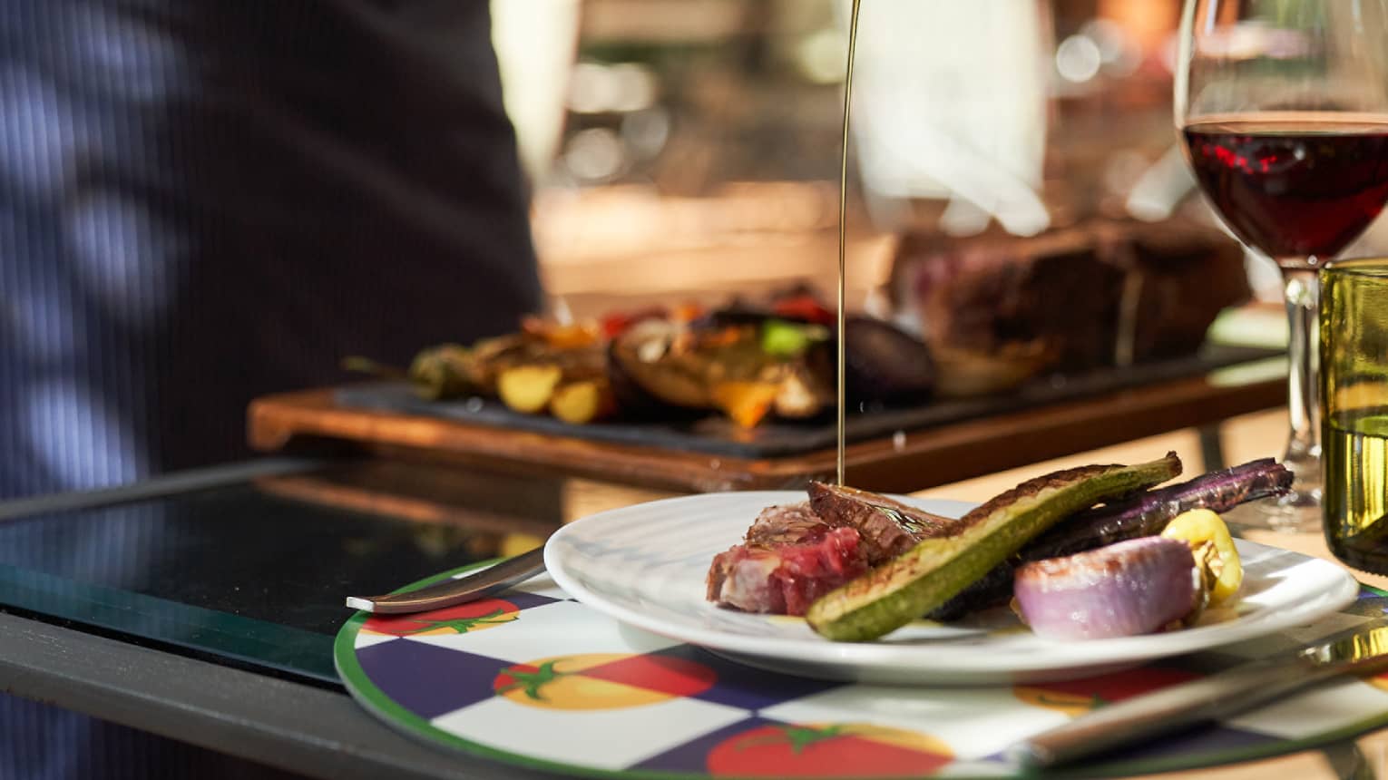Chef pouring olive oil over plate of grilled vegetables