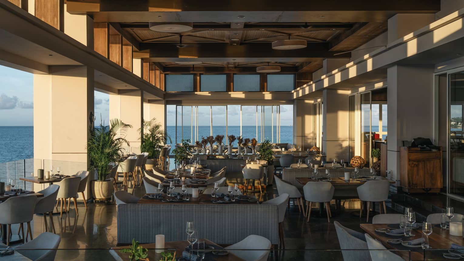 Dining room with floor-to-ceiling windows and views of the ocean.