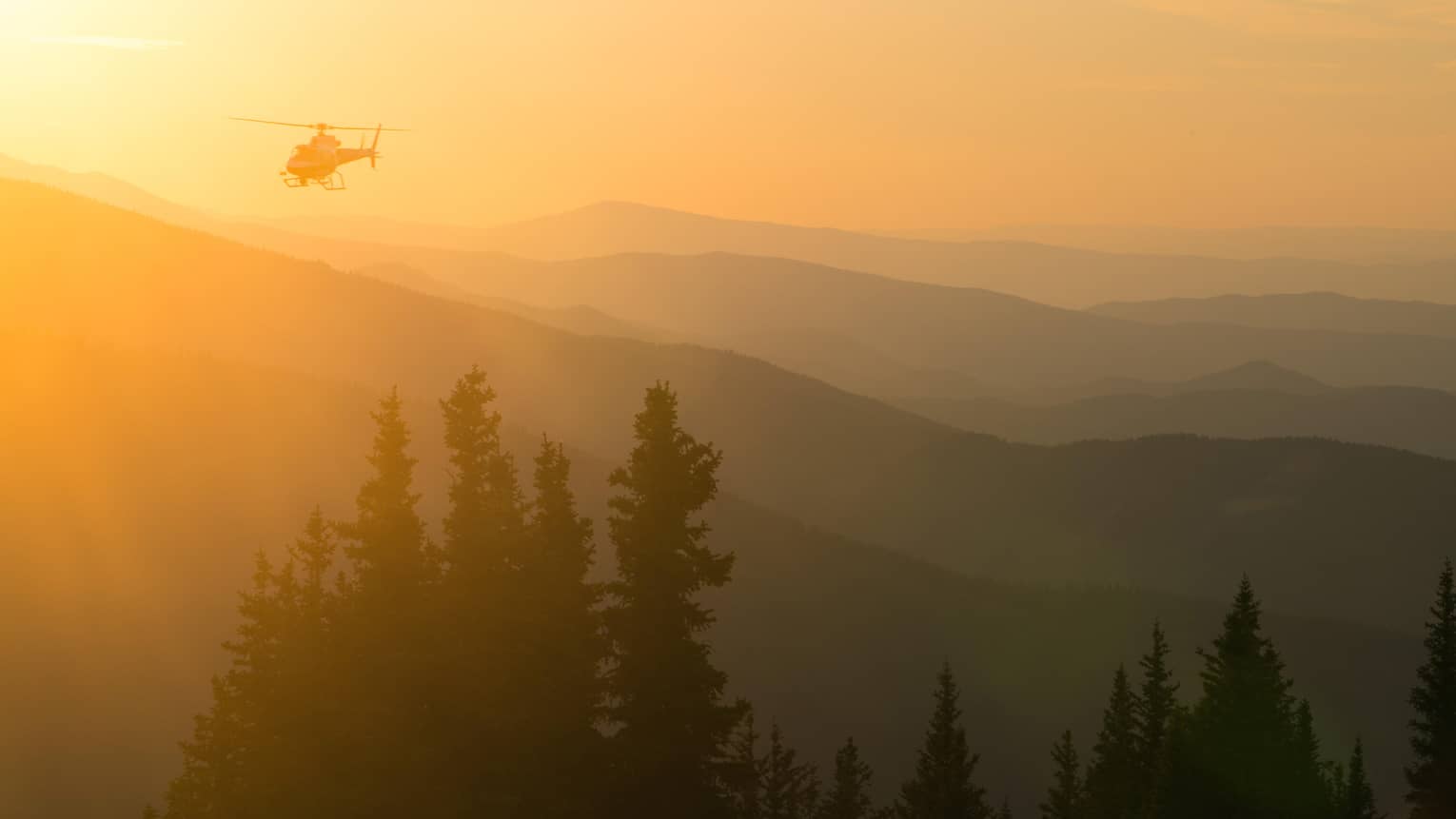 Helicopter at sunset flying over Aspen Mountain in the Elks Mountain range