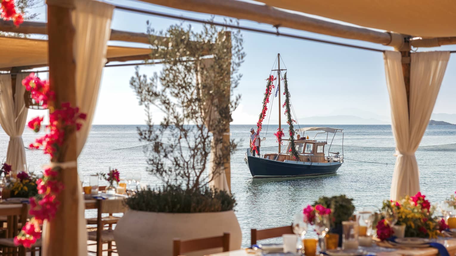 View of sailboat on calm Saronic Gulf through waterfront restaurant patio of Taverna 37