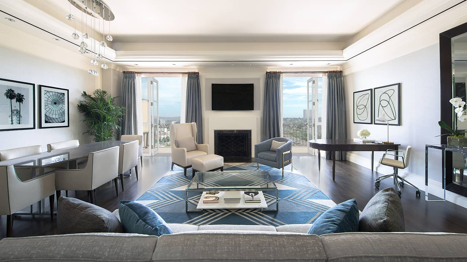 Ambassador Suite back of long sofa, dining table, armchairs by fireplace, TV, open balcony doors