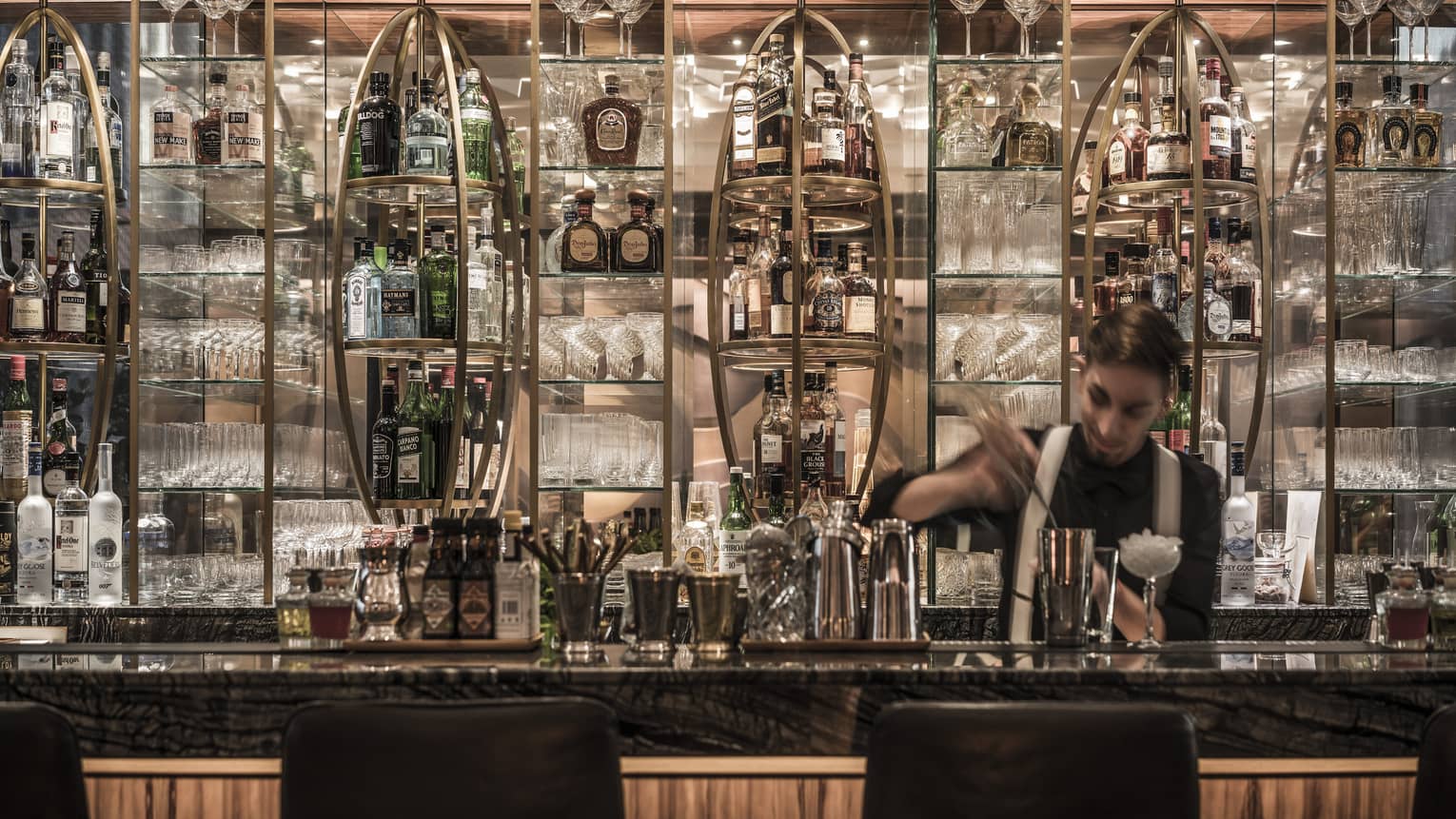 Bartender mixing drink in front of elaborate liquor display behind bar at Luna Sky Bar lounge