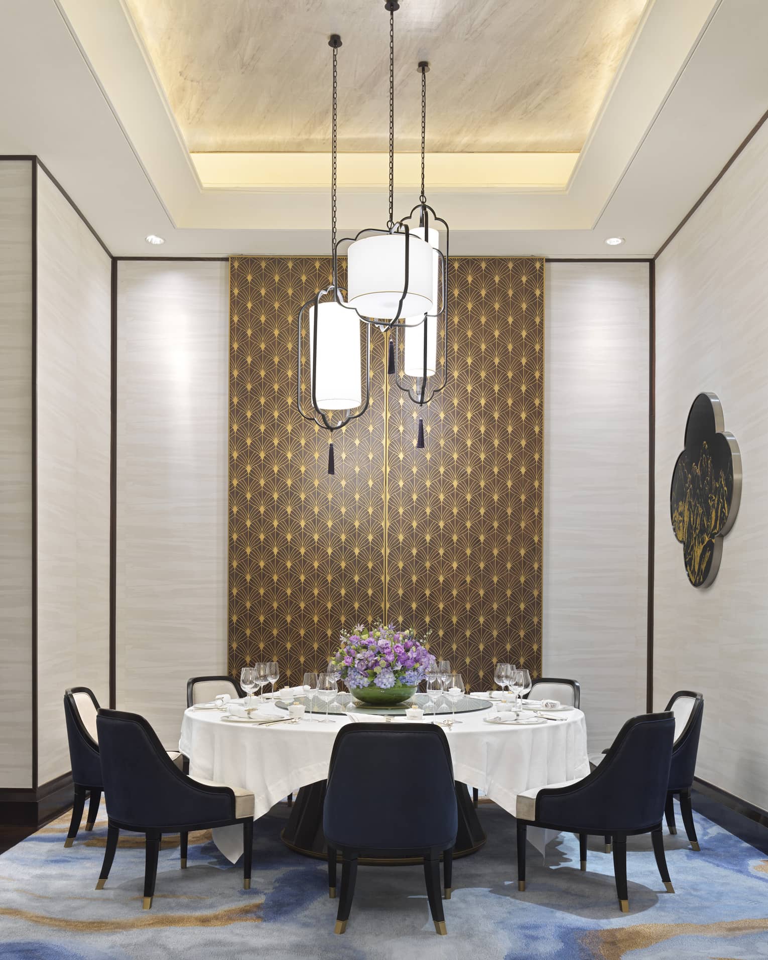 Zi Yat Heen private dining room with round table and white linens, eight blue chairs, watercolour carpeting, triple light fixtures from ceiling