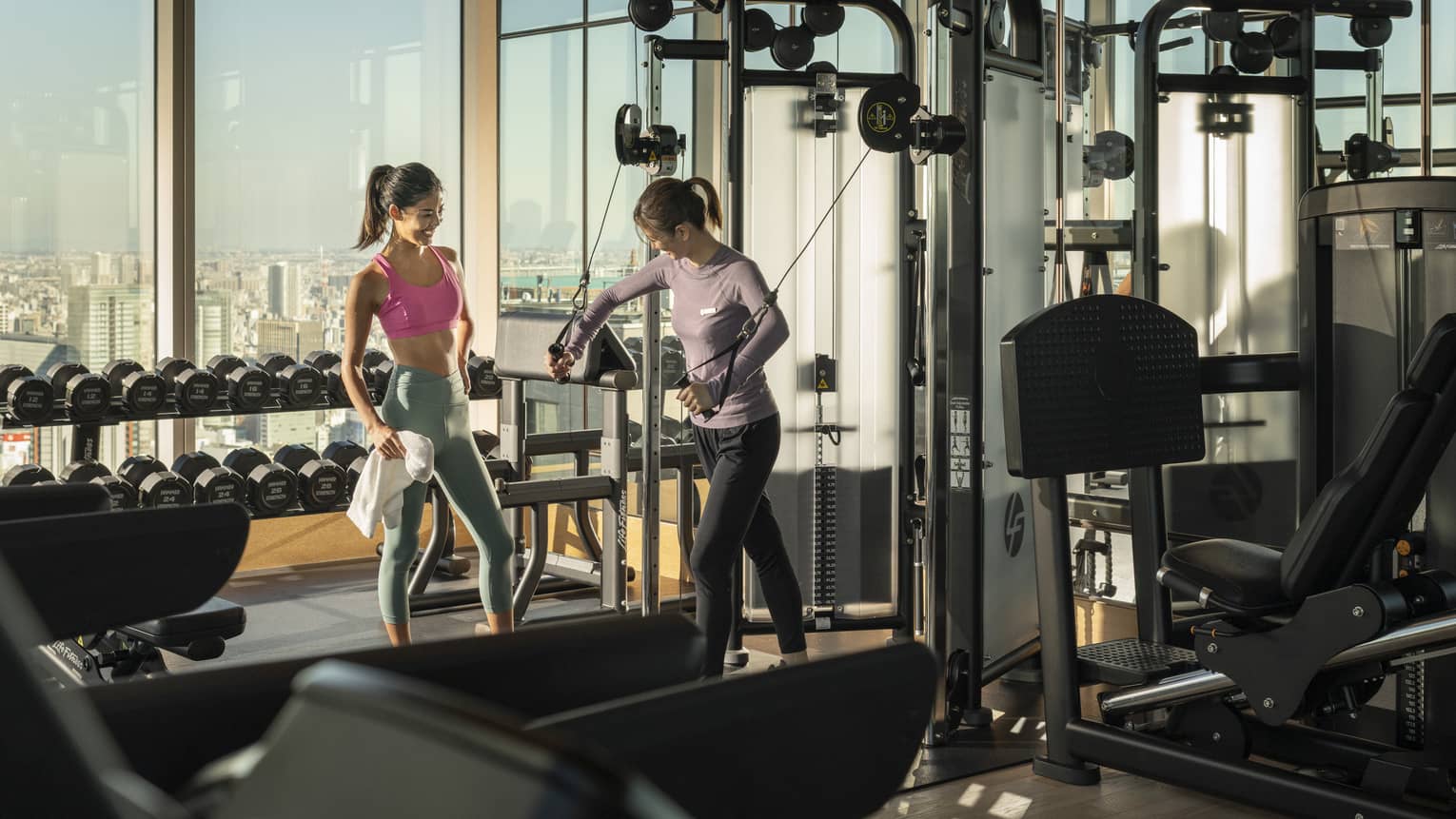 Trainer shows woman how to use exercise machine during a private session