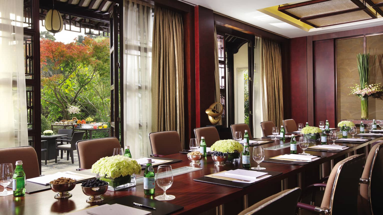 Long private business meeting table near tall open doors to patio