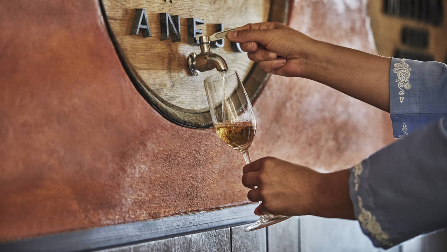 Woman pours tequila from tap into wine glass 