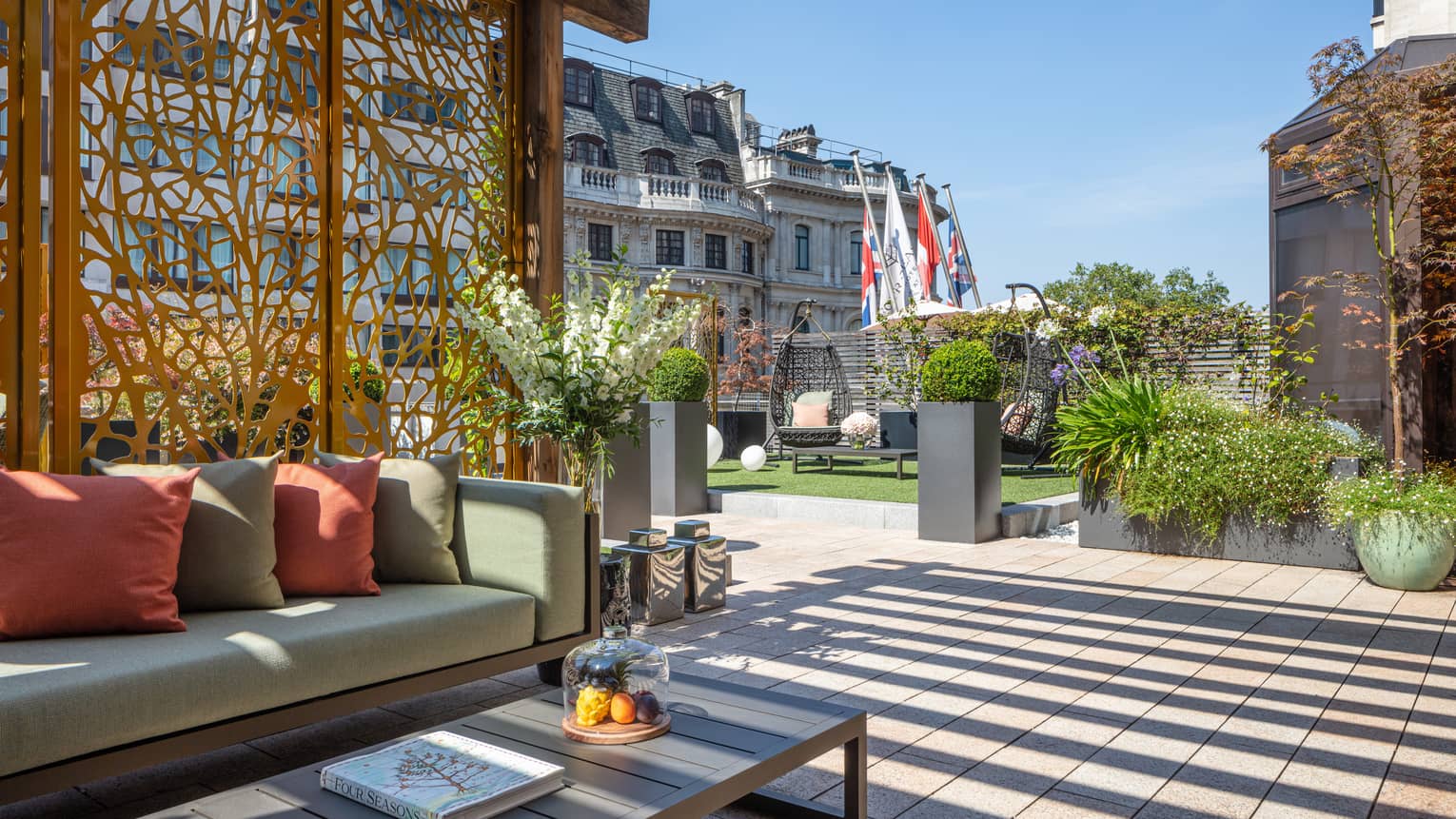 Patio with sofa and throw cushions, coffee table under pergola with screen
