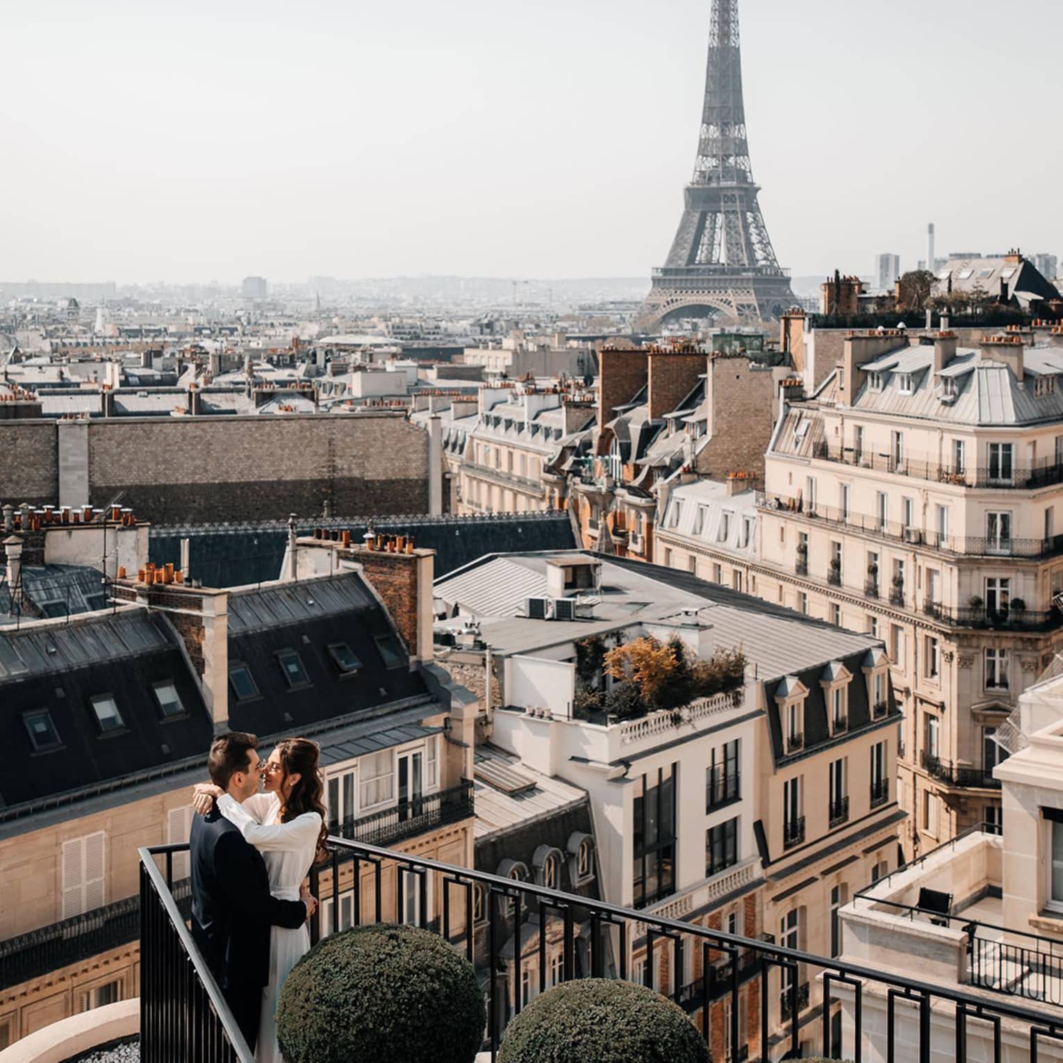 Couple embracing on Paris Hotel terrace with Eiffel Tower view