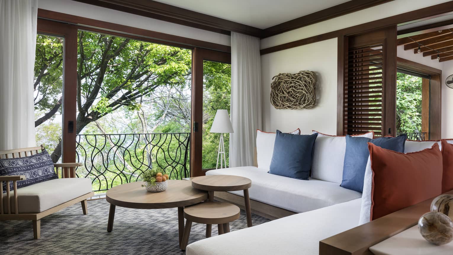 Pacifico Two-Bedroom Resort Residence living room with white L-shaped sofa, three-tiered table by large open wall