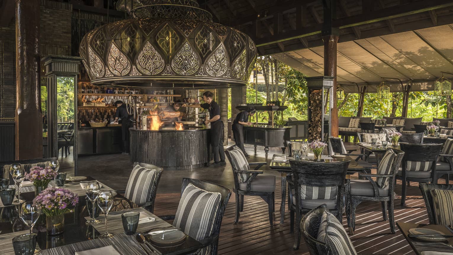 Restaurant with fire in open kitchen, dark wood floors and dining table/chairs