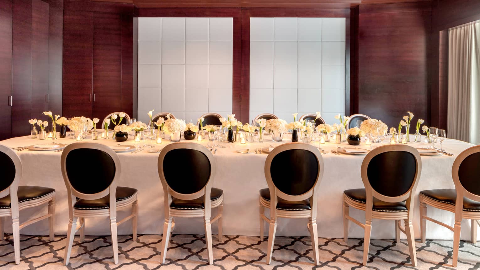 Meeting room set with white linens and black padded chairs 