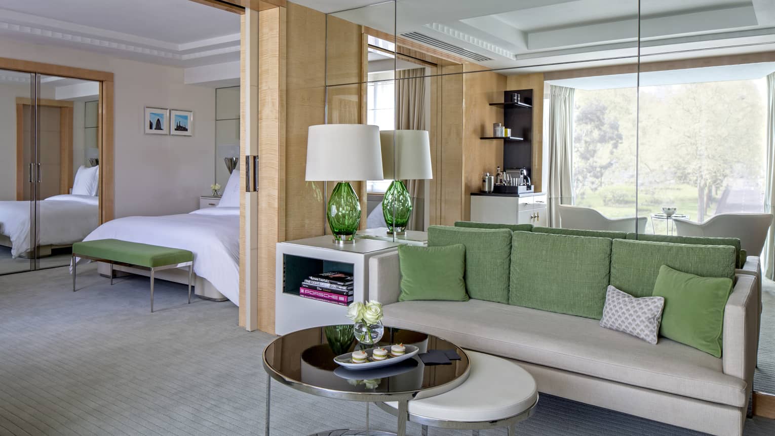 Mayfair Suite grey sofa with green pillows, round tables, alcove with bed, mirror