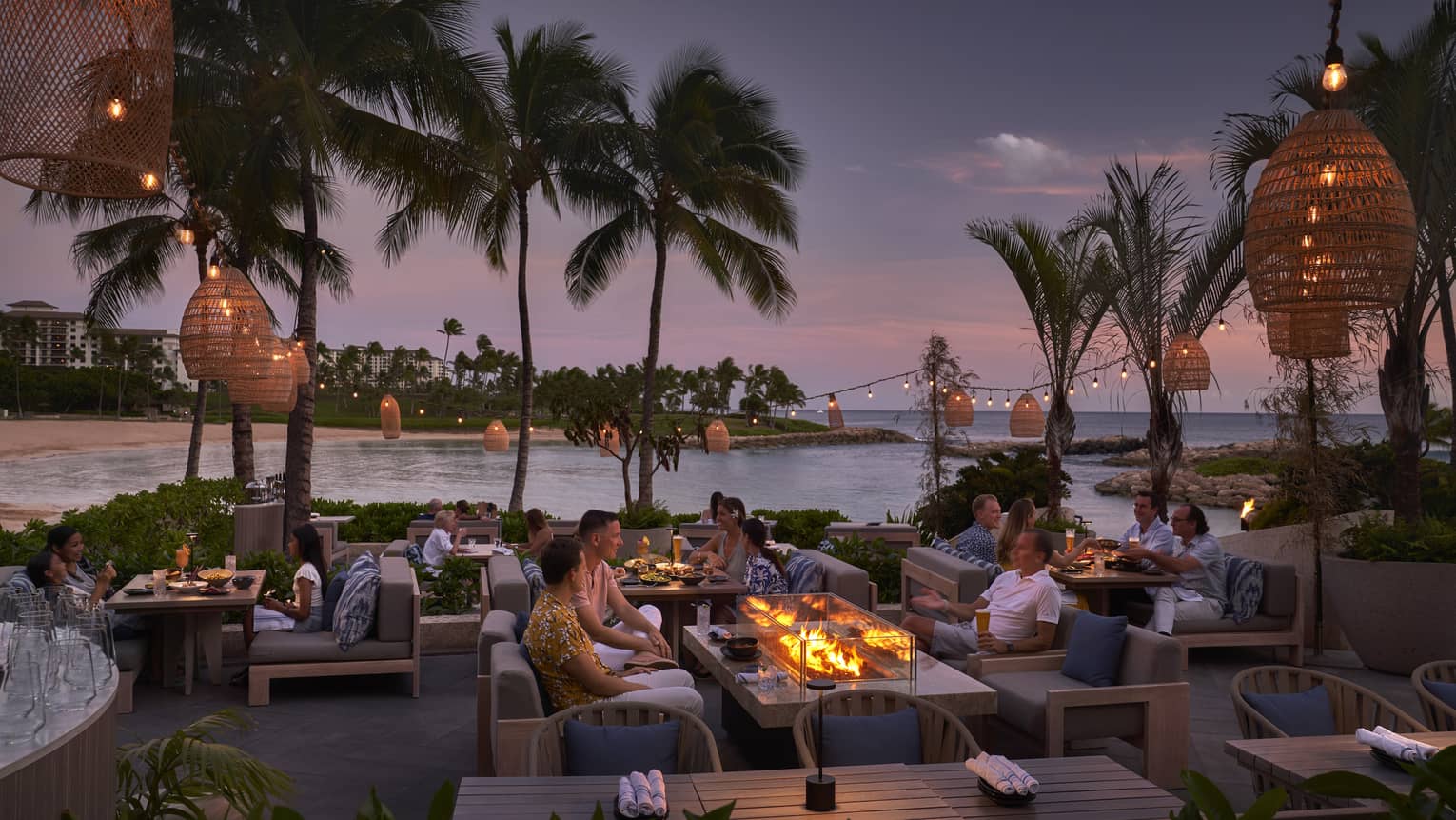 People mingling on outdoor, waterfront terrace in tropical location at night