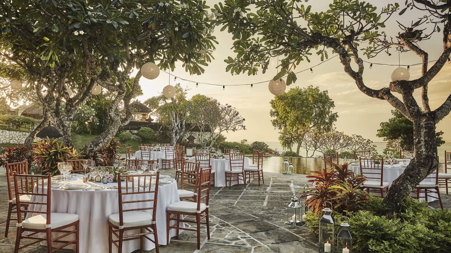 Patio wedding reception at sunset, small round banquet tables and chairs under trees