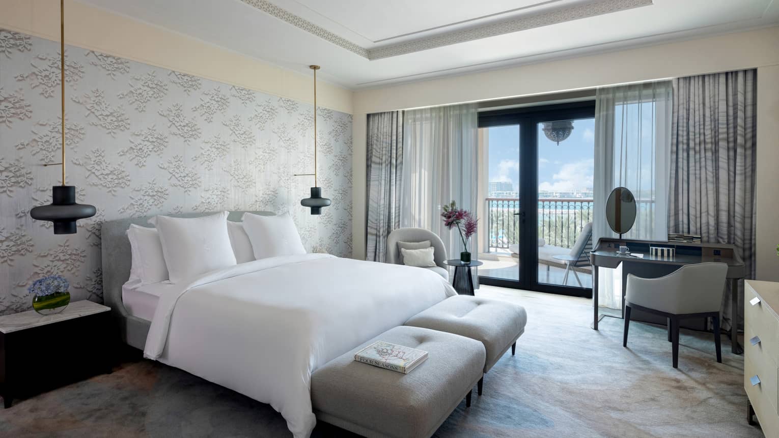 Bedroom with wall-papered accent wall, king bed, two hanging sconces