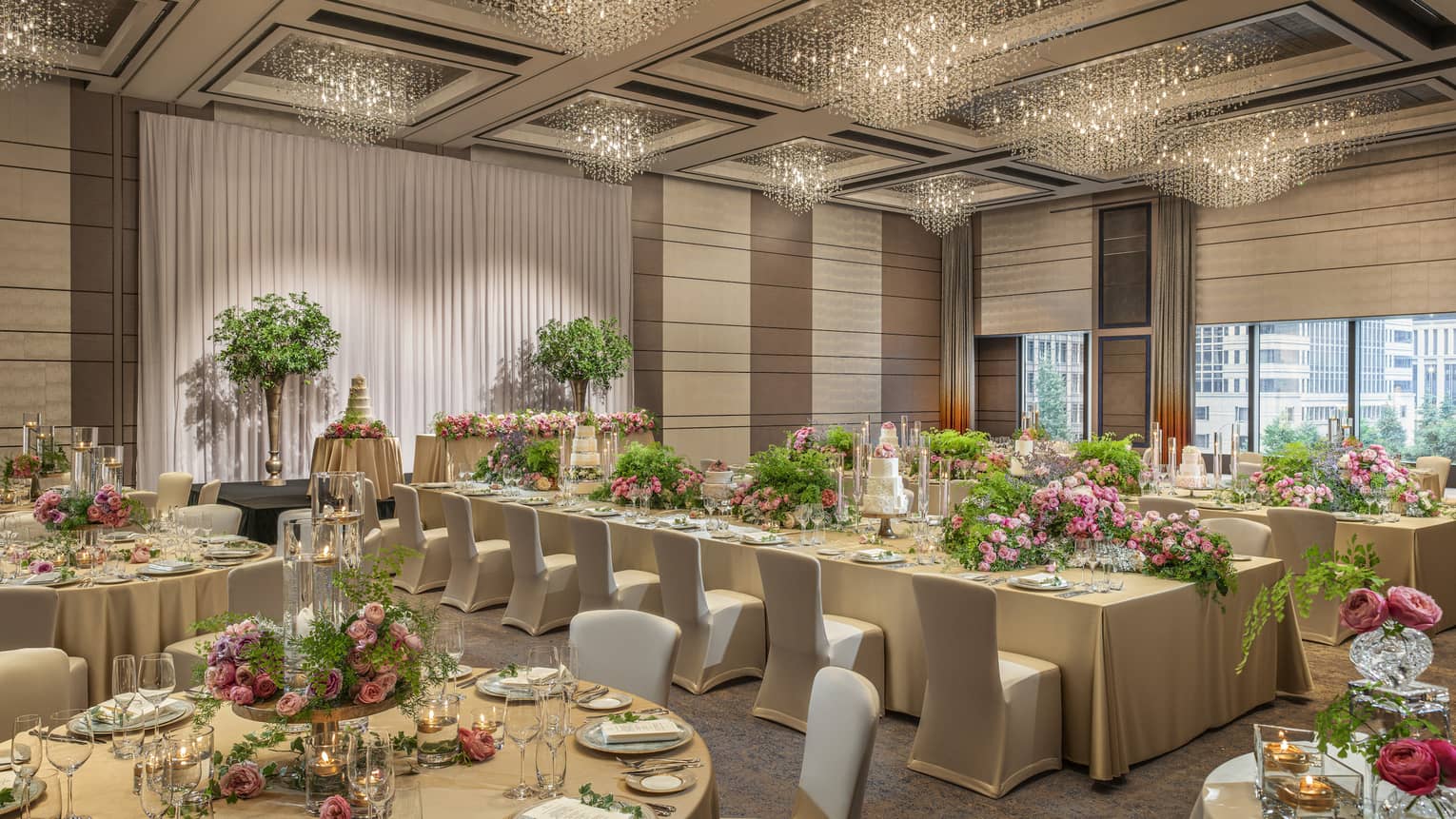 Ballroom set for a wedding with gold tablecloths and pink floral centrepieces