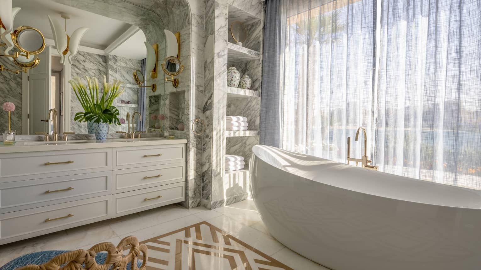 The Palace bathroom with large soaking tub, marble walls, double vanity, built-in shelves