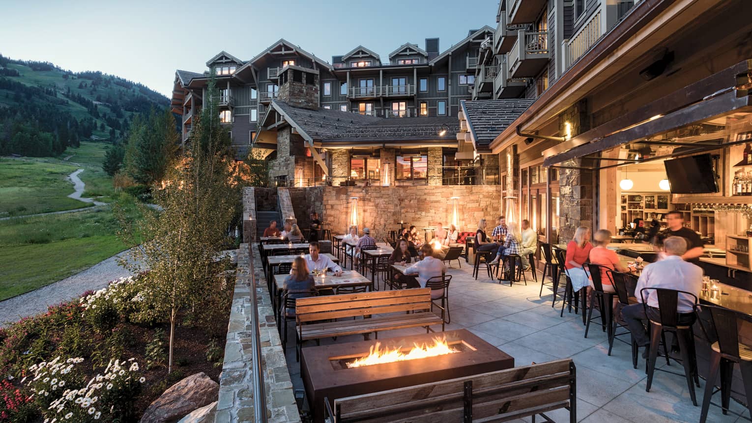 Outdoor patio of Handle Bar restaurant/pub with firepit, tables and bar seating with mountain view