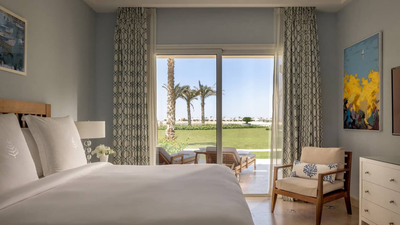 Guest bedroom with king bed, armchair, sliding glass door to terrace