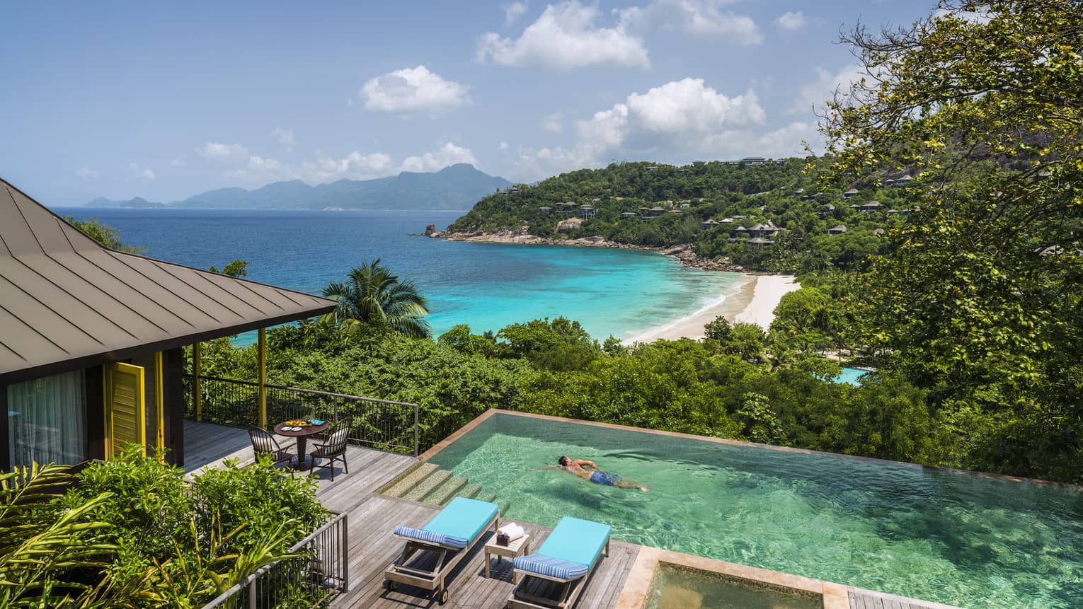 Two-bedroom Ocean View Suite deck, man swims laps in plunge pool, ocean and beach seen below