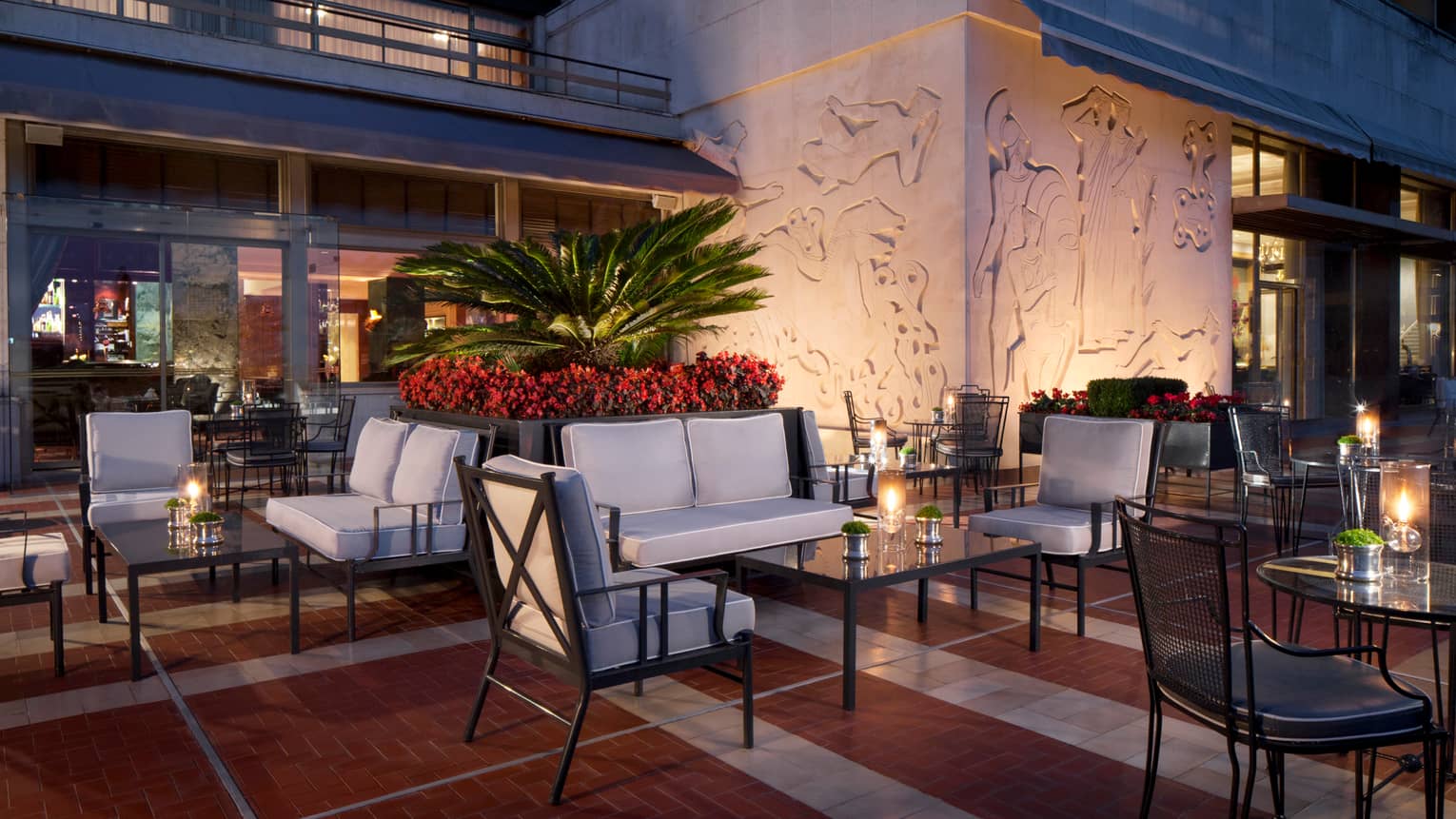 Ritz Bar outdoor patio lounge at night with cushioned chairs and loveseats around candle-lit cocktail tables