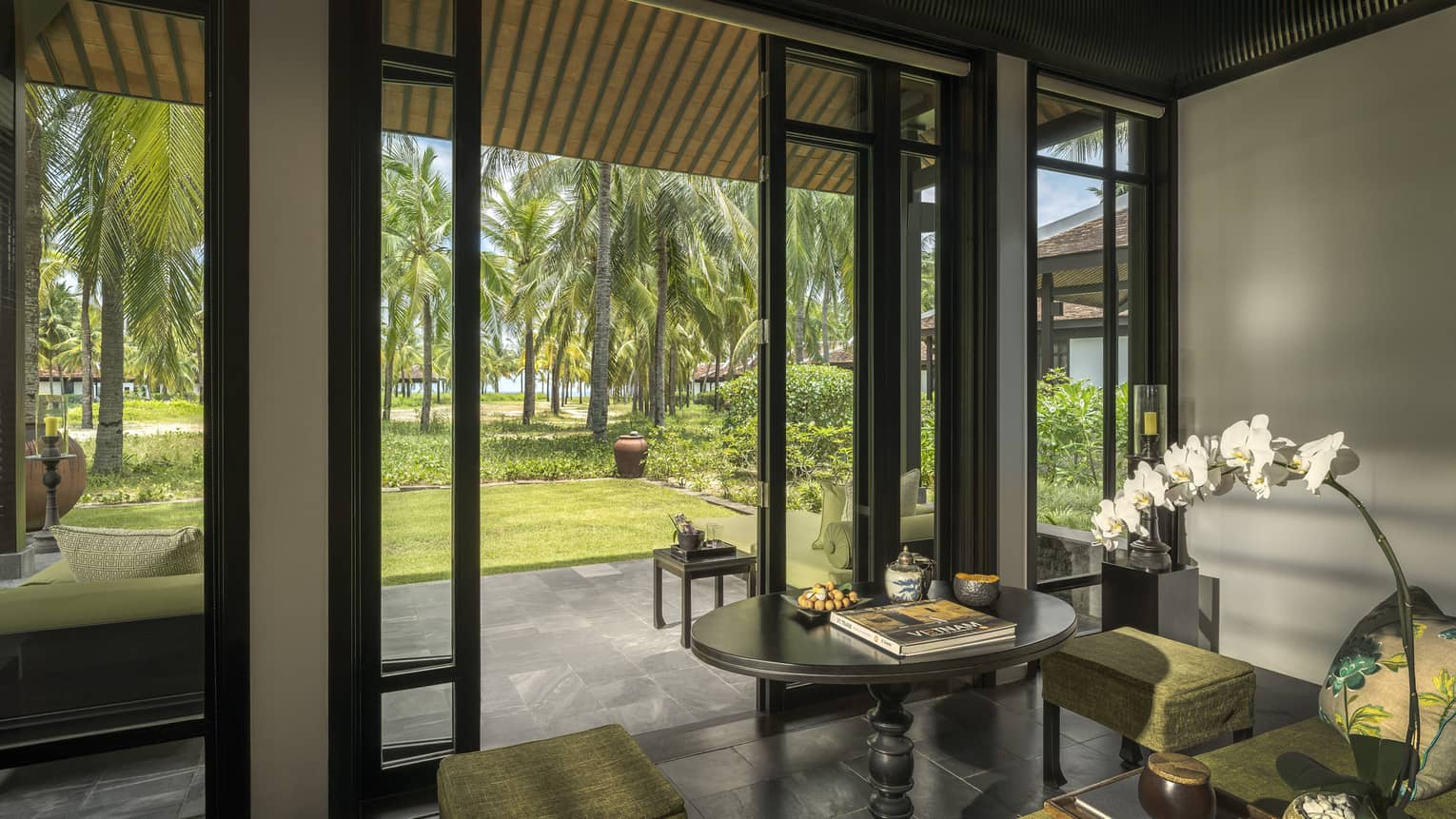 Family Villa living area opening on stone floor veranda with palm tree views