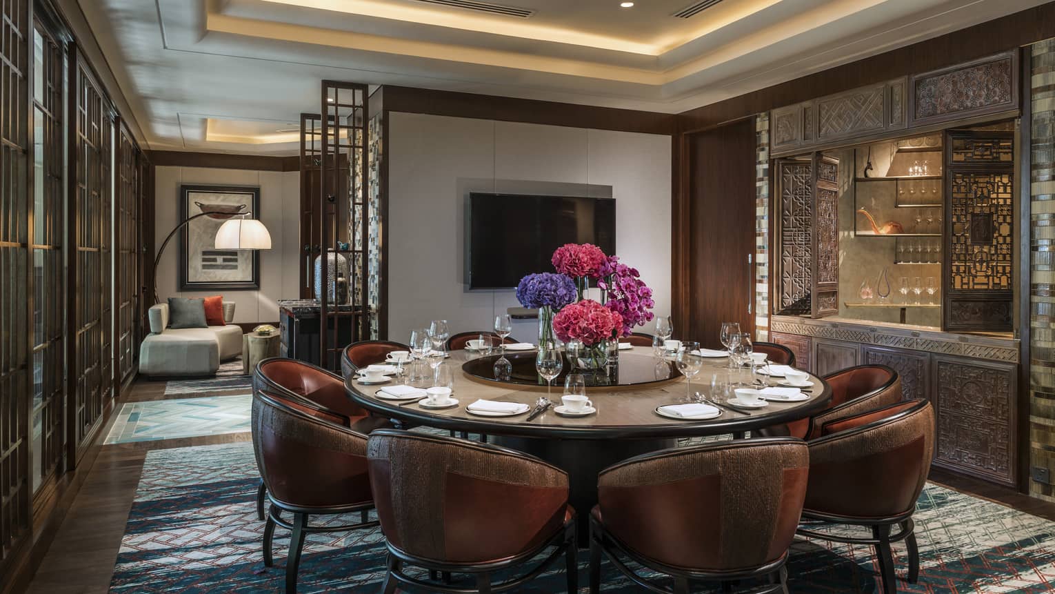 Leather bucket chairs around private meeting dining table, TV on wall