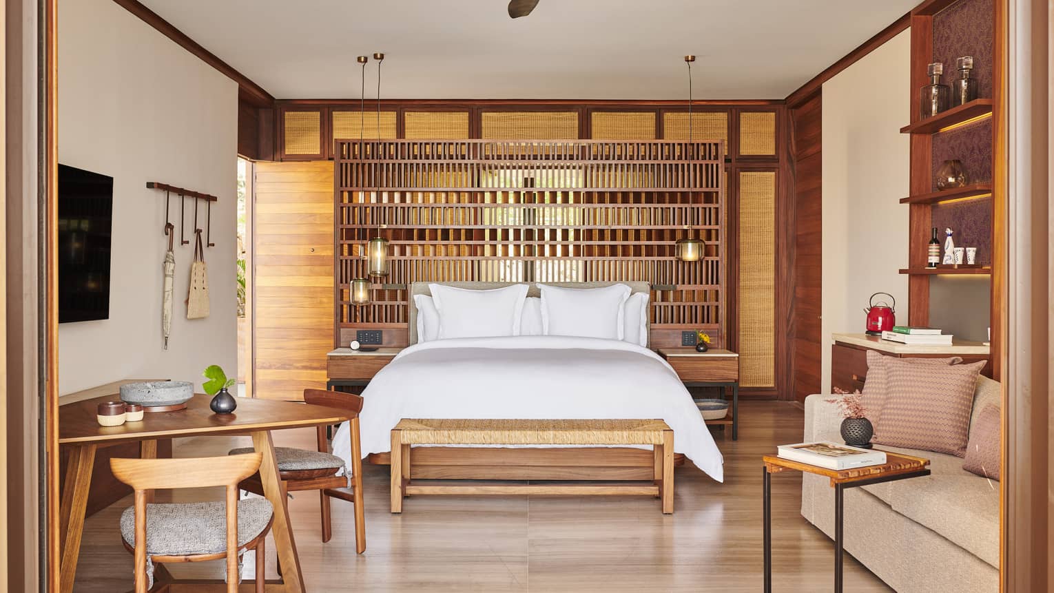The interior of a beachfront room with a bed, shelves, small tables, chairs and sofa.