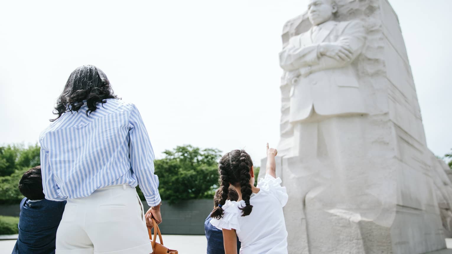 A woman and three children looking at the Martin Luther King, Jr. Memorial on a sunny day.