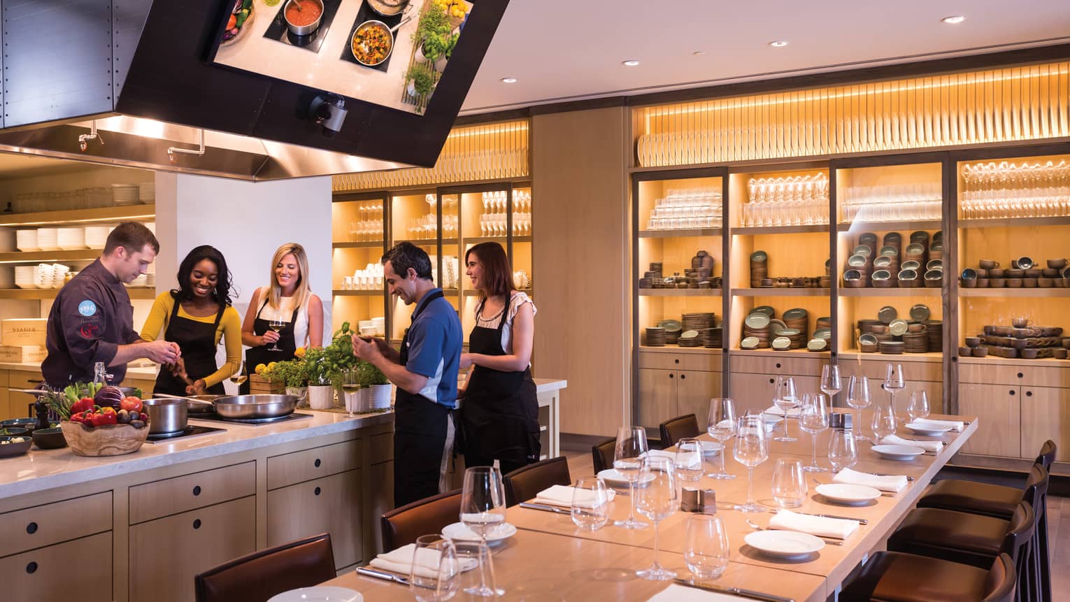 People wearing aprons gather around counter in Ravello Demonstration Kitchen 