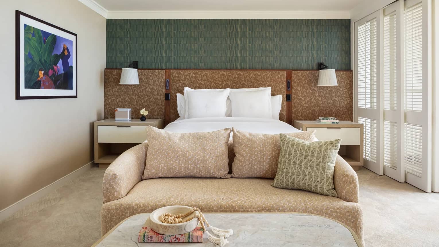 Resort room featuring a king bed, small sofa at the foot of the bed and coffee table