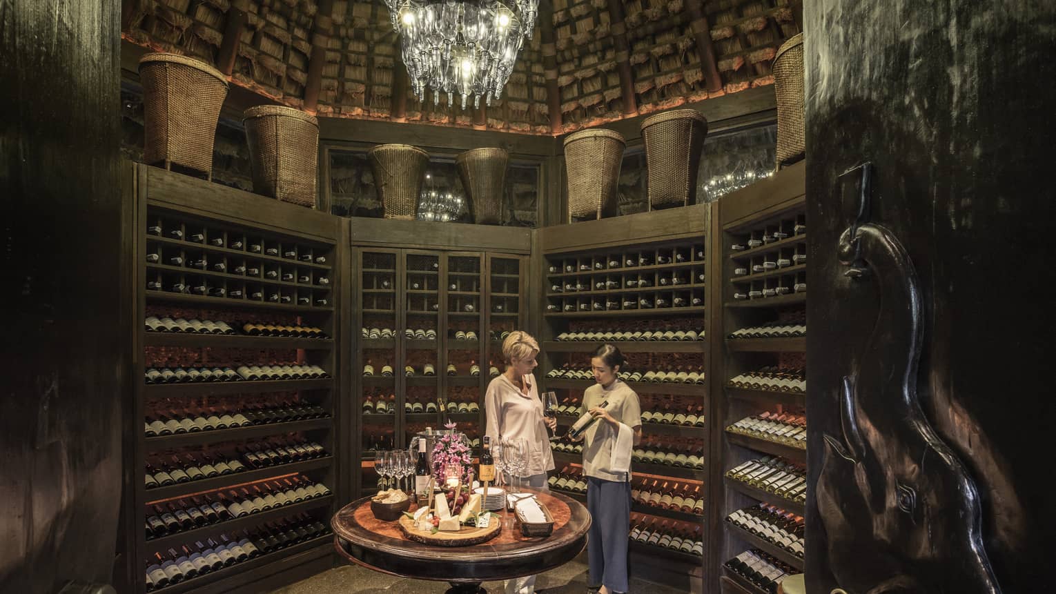 Two people examine wine bottles in Camp Wine Cellar