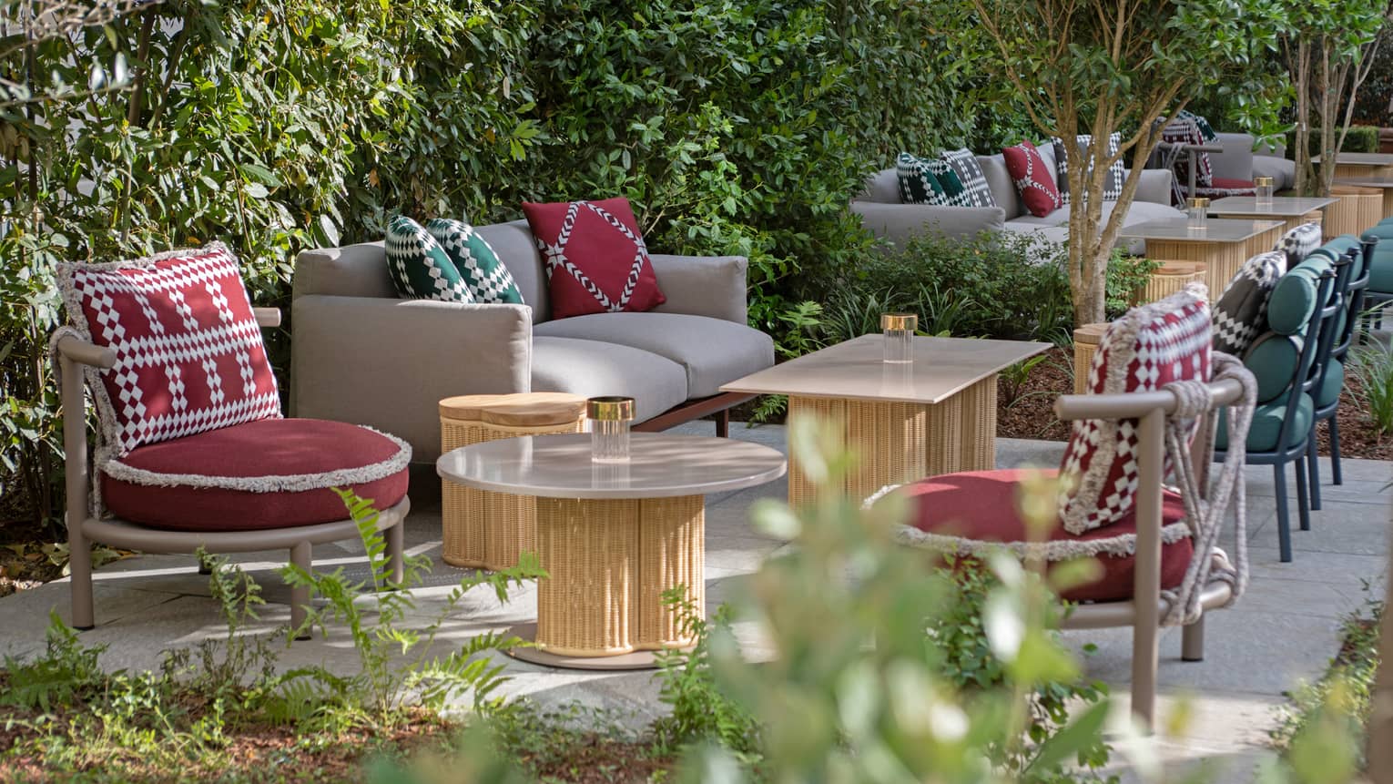 Stilla Garden restaurant patio with wooden tables, red chairs, tan couches with red and green pillows